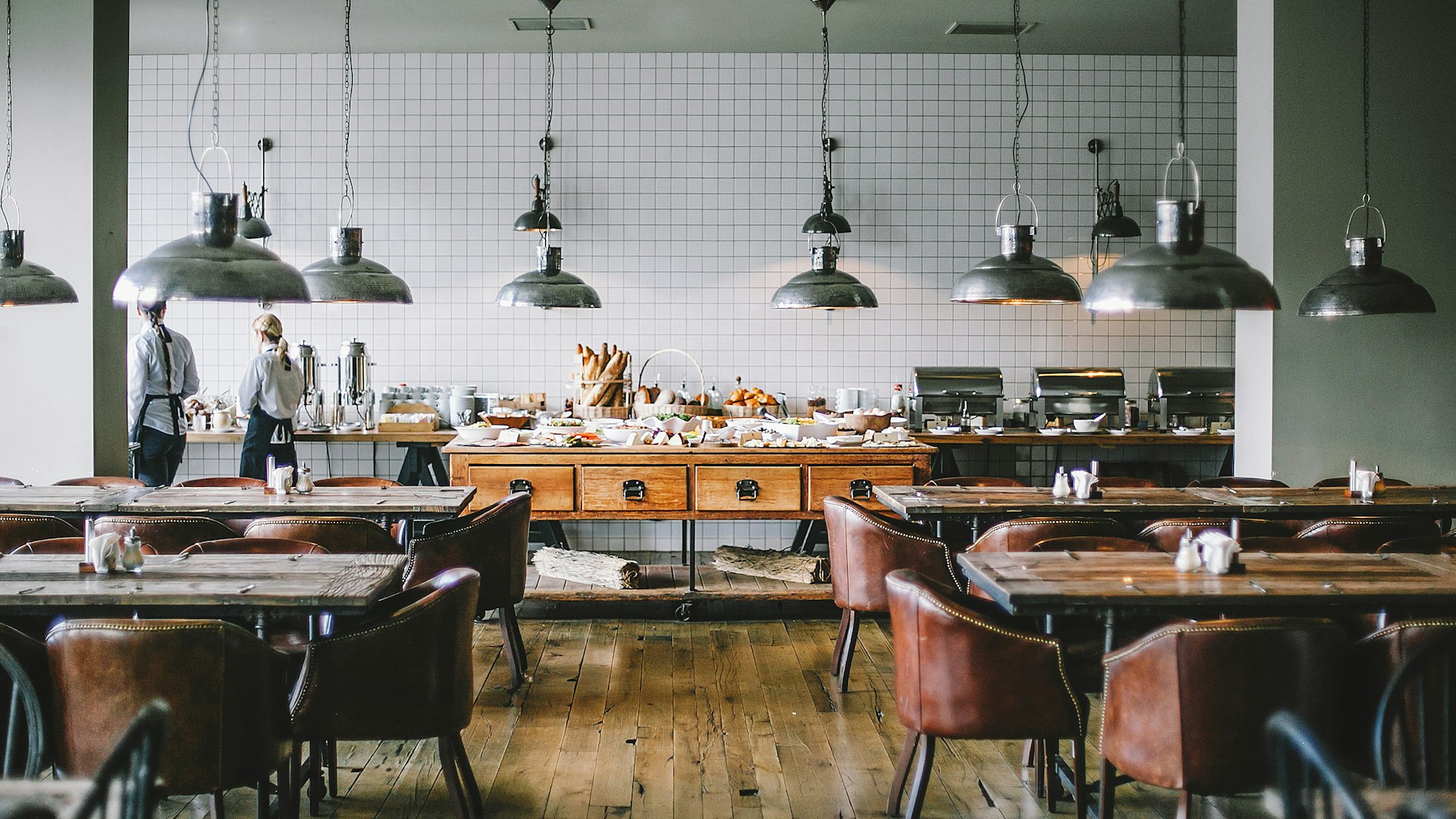 Warmes Restaurant-Interieur mit Holztischen und Industrielampen